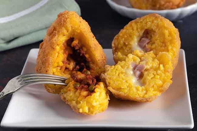 Arancini detail, traditional Italian food, mostly Sicilian, one stuffed with meat and peas ragu and another, so-called butter, stuffed with ham and mozzarella cheese.