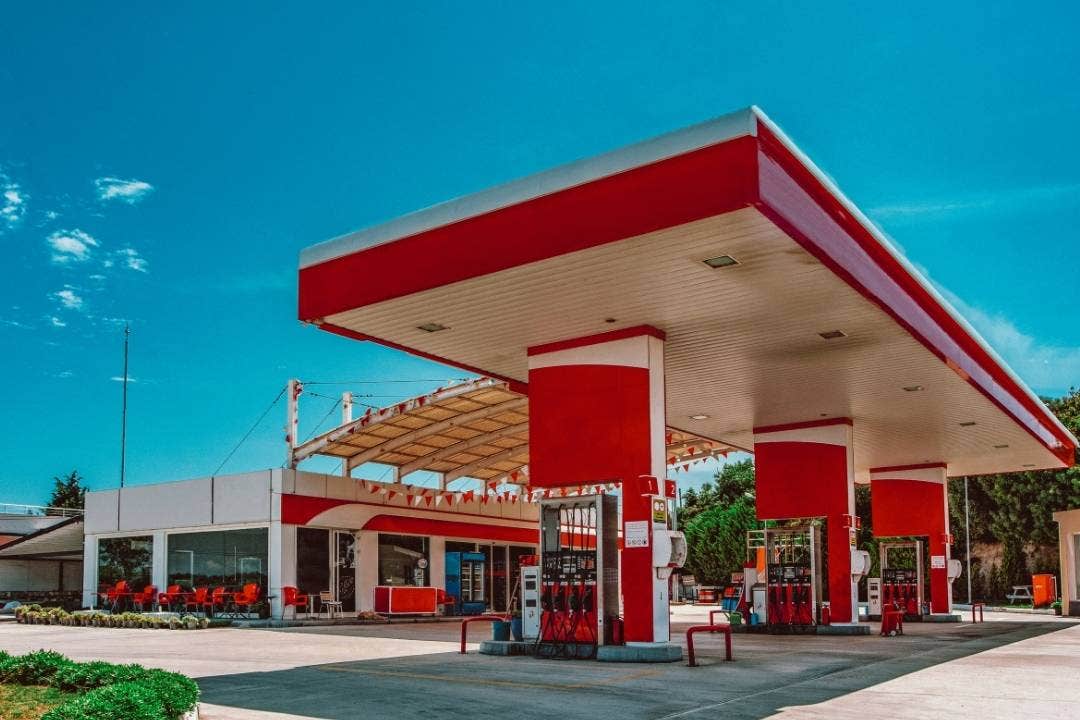 Modern gas station with red accents under a bright blue sky