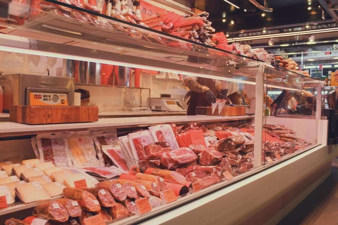 Butcher shop counter with sealed meat cuts and a hot film wrap machine on display.