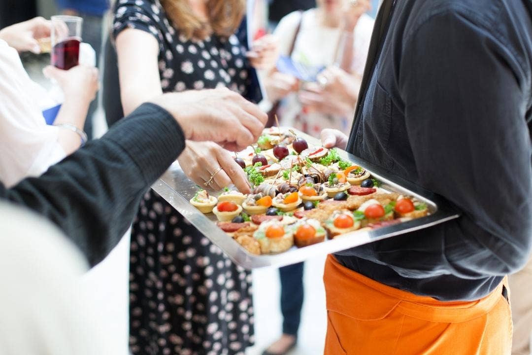 Caterer offering assorted appetizers on a tray at a formal gathering