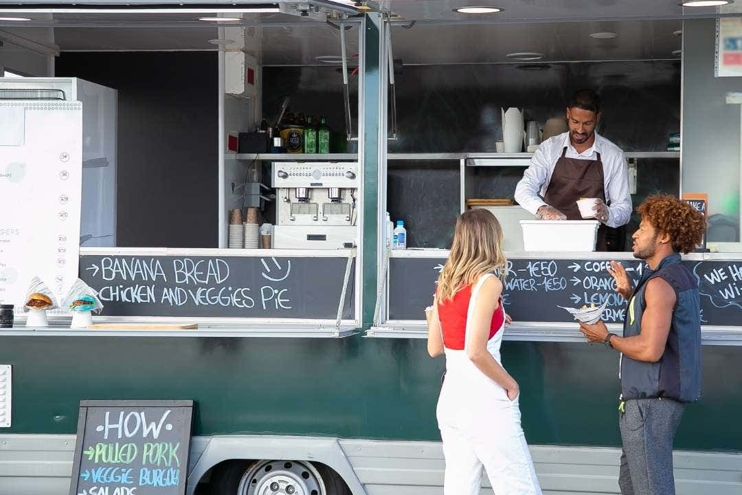 Food truck vendor serving customers at an outdoor mobile kitchen setup