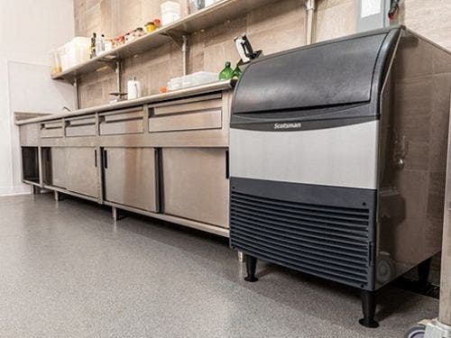 A Scotsman undercounter ice machine in a commercial kitchen next to a work table.
