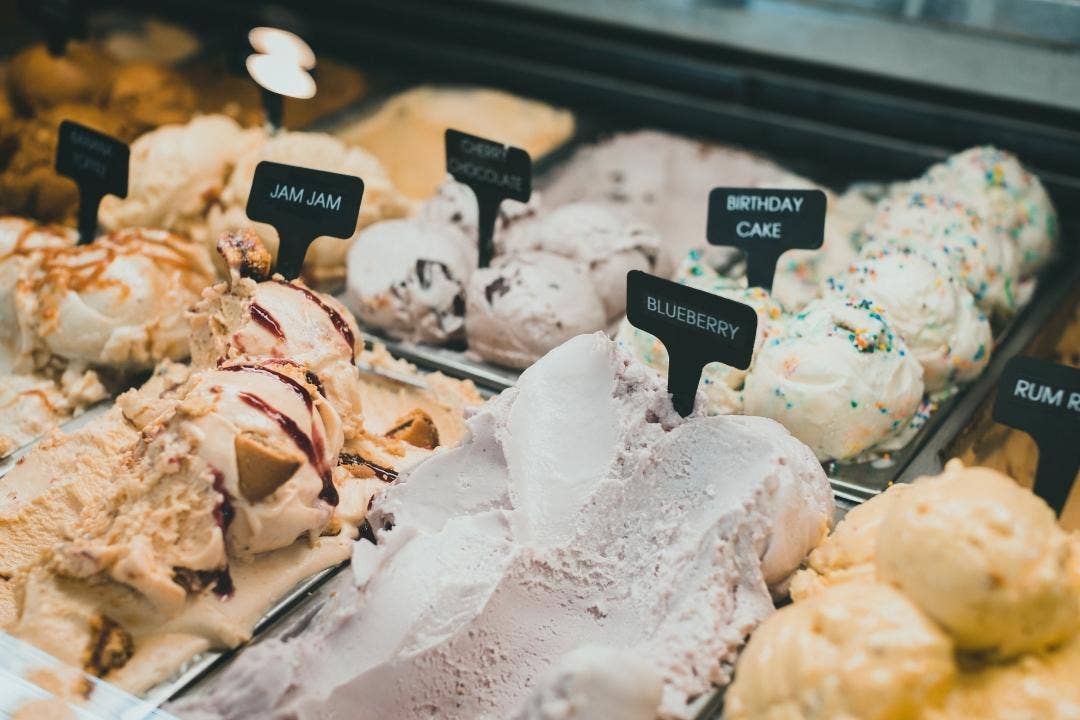 Colorful variety of ice cream flavors labeled in a commercial freezer display.