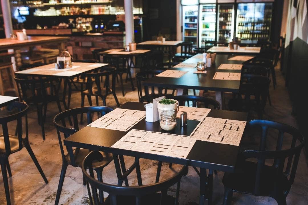 Modern restaurant dining area with set tables and overhead ambient lighting.