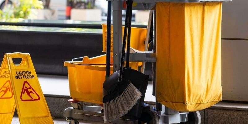 Janitors cart with a mop, bucket, broom, dustpan, and wet floor sign.