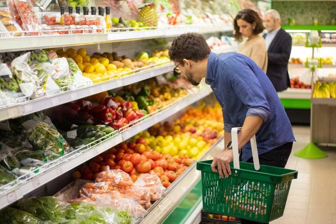 Man shopping for fresh produce in grocery store fruit and vegetable aisle