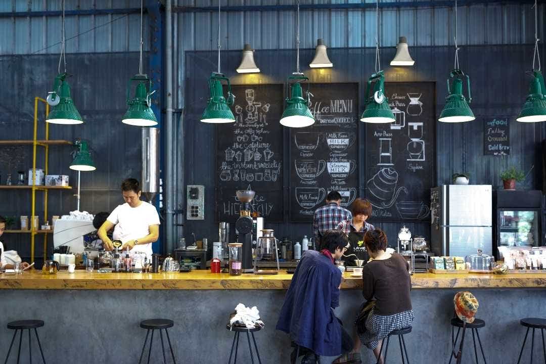 Trendy coffee shop with baristas brewing and customers at counter