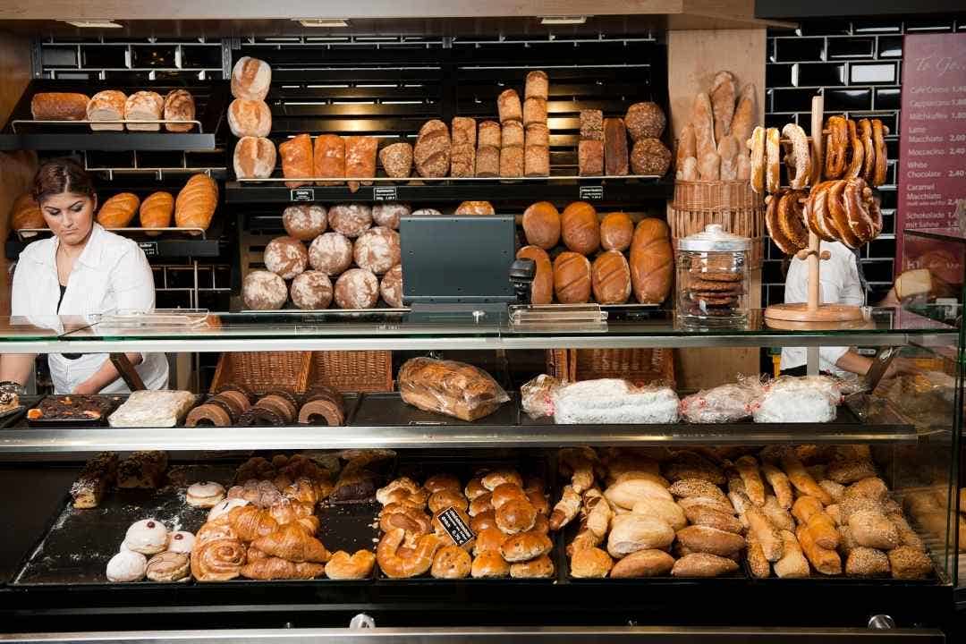 Bakery display with assorted breads, pretzels, and pastries behind glass.