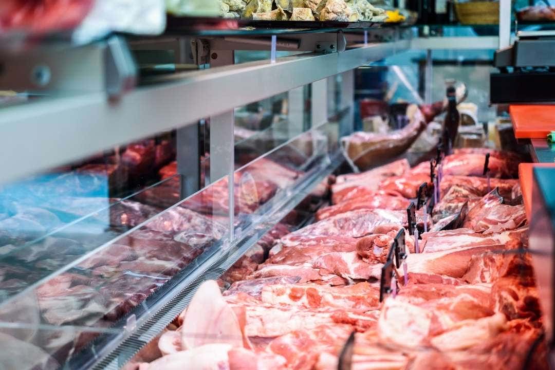 Butcher shop meat case filled with fresh cuts behind a glass display.
