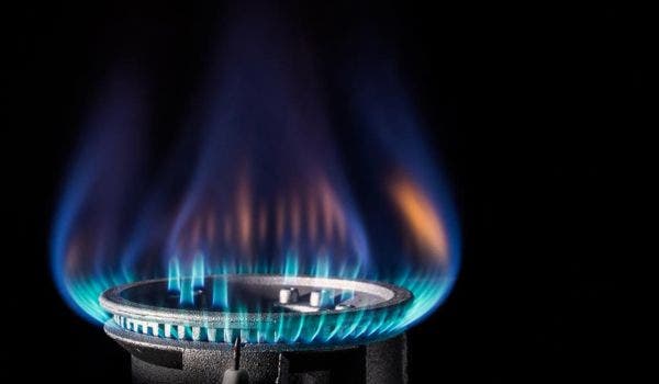 Close-up of a gas burner with a bright blue flame on a stovetop.