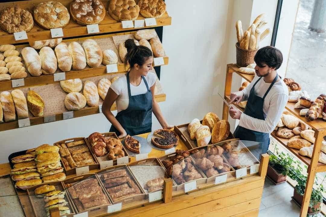 Bakery display with bread, pastries, and staff behind the counter serving customers.