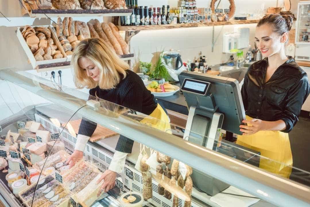 Staff serving cheese and meats at local deli shop