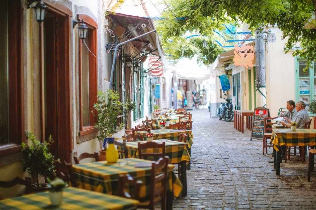 Outdoor café tables with checkered tablecloths on charming cobblestone street
