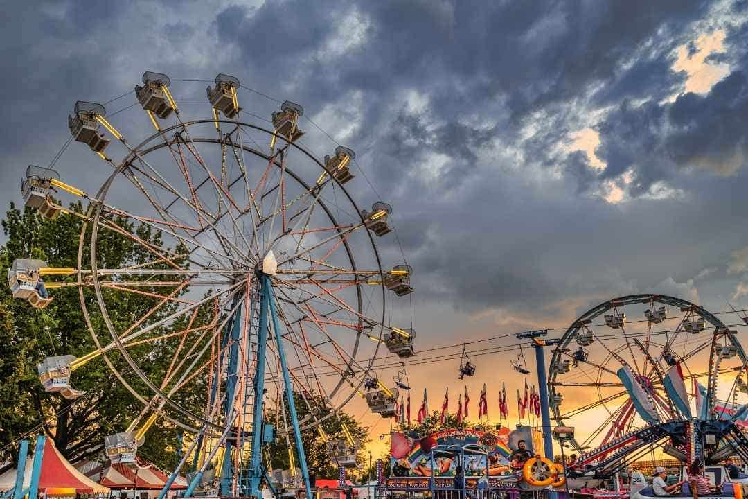 Ferris wheel and carnival rides at sunset during a lively amusement park event