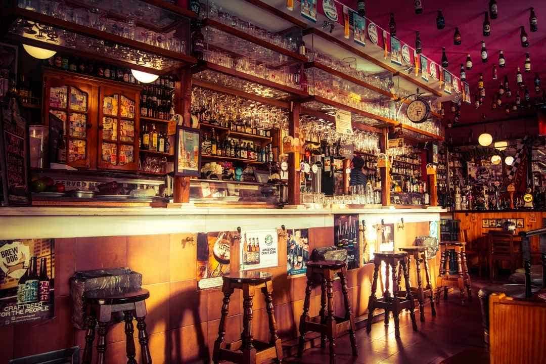 Cozy bar interior with stools, hanging glasses, and a wide variety of drinks