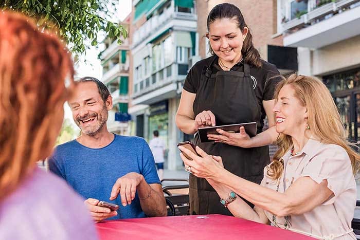 mature group order food in restaurant. waitress using smartphone and tablet application technology