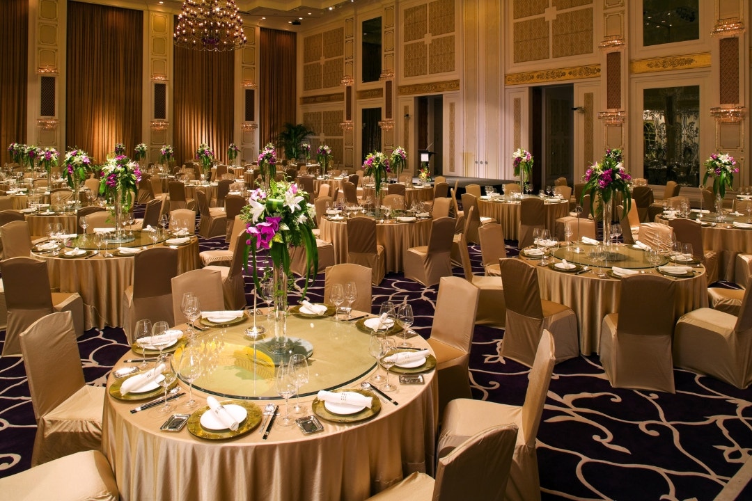 Lavish banquet hall set with round tables and floral centerpieces