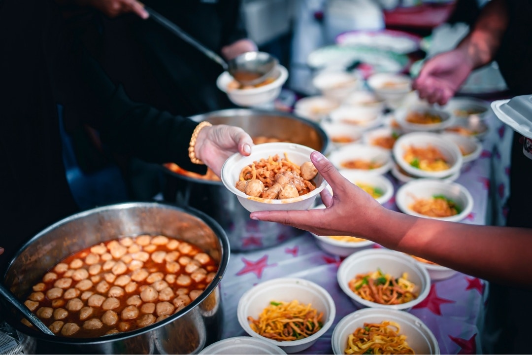 Community food kitchen serving hot noodle and meatball bowls.