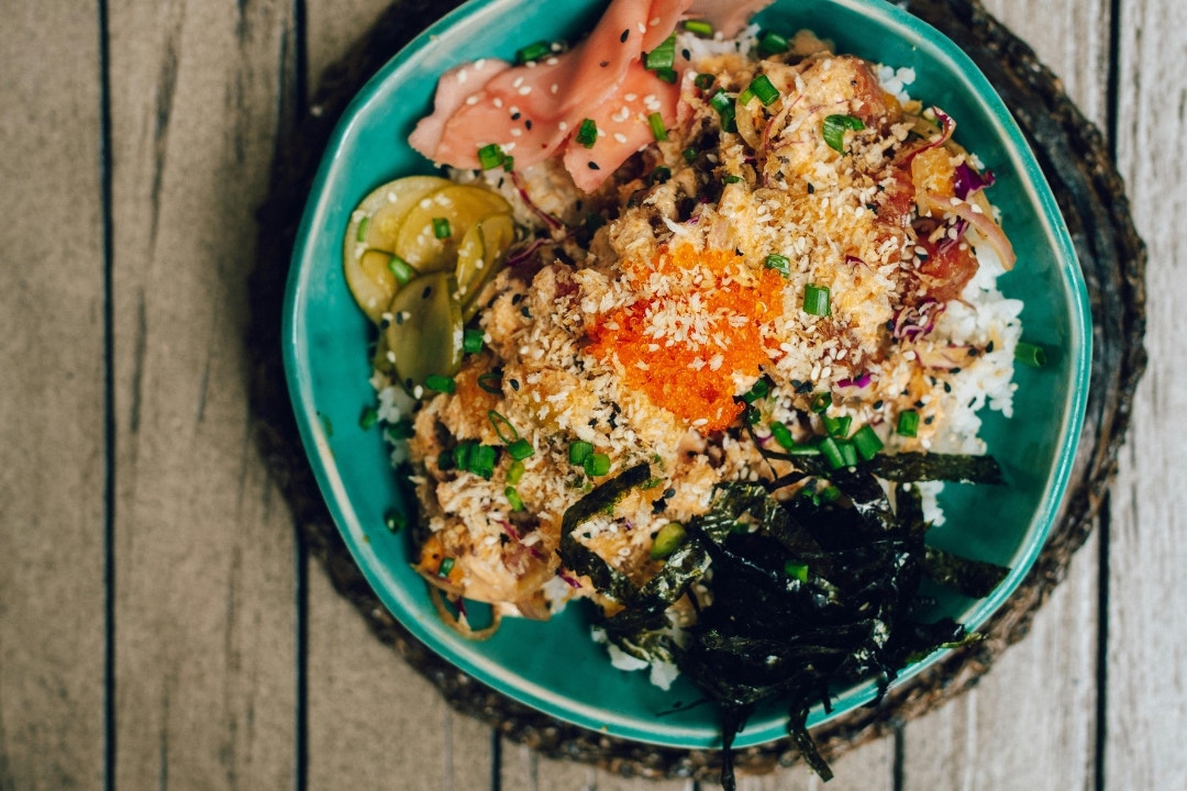 Colorful Asian fusion rice bowl with pickled vegetables and crispy toppings.