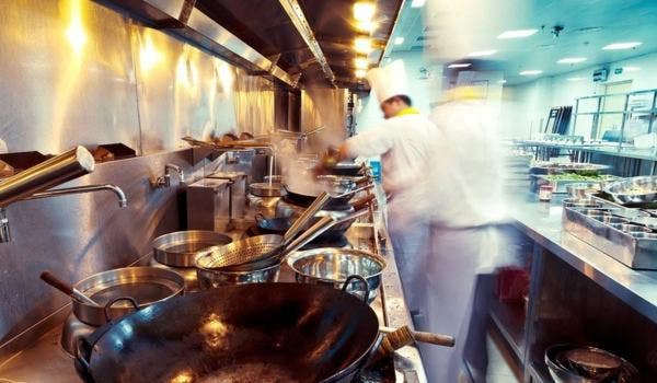 Busy kitchen with chefs cooking food in a commercial kitchen.