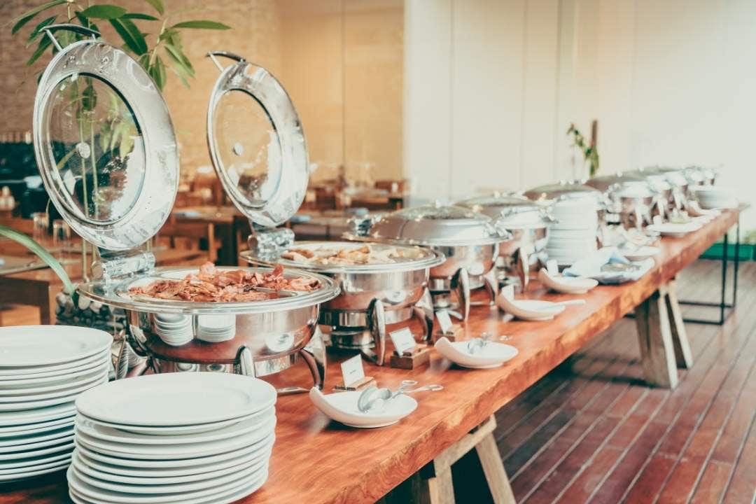 Buffet line with chafing dishes and plates at catering event setup