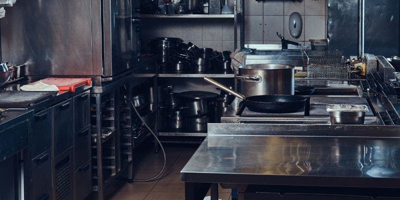 Commercial kitchen with prep tables, shelving and storage.