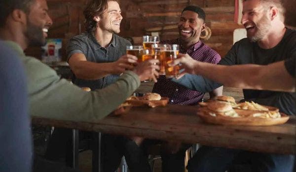 Group of friends toasting with beer glasses at a cozy pub.