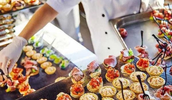 Caterer arranging beautifully plated appetizers on a tray for an event.