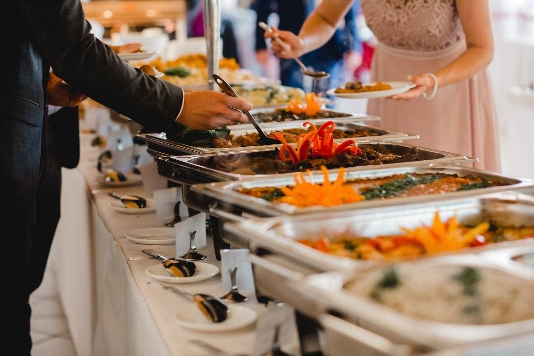 Guests serving food from a hot steam table buffet at a formal event