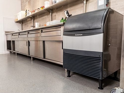 A Scotsman undercounter ice machine in a commercial kitchen next to a work table.