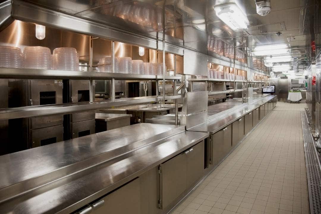 Large institutional stainless steel kitchen setup for bulk food slicing and prep