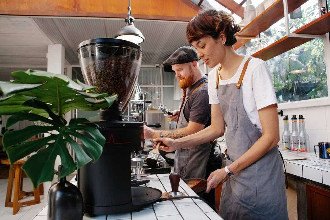 Baristas preparing coffee at a modern dessert shop counter with coffee grinder