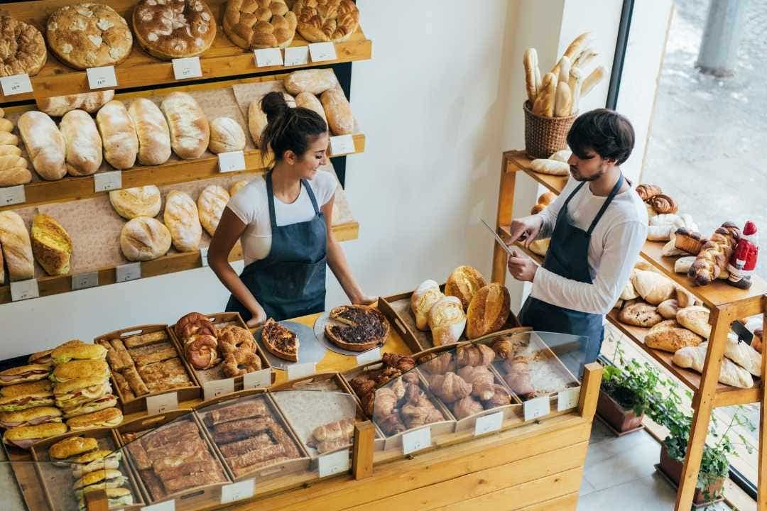 Bakery staff serving customers fresh bread and pastries.