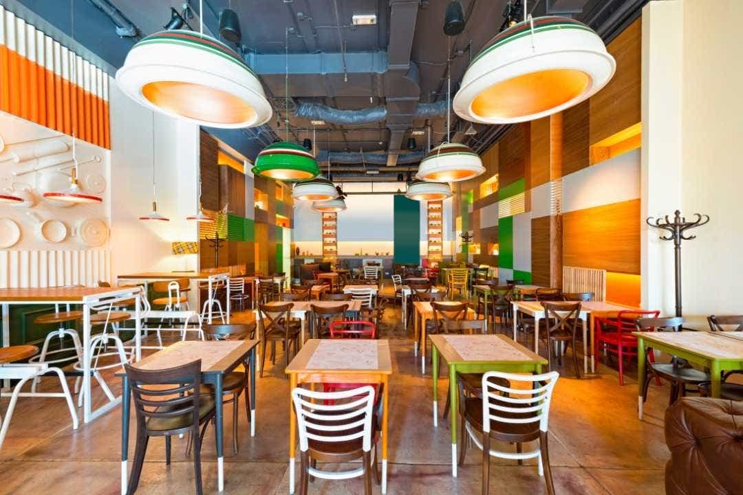 Modern restaurant dining area with eclectic chairs and lighting.