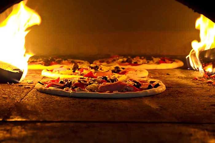 Pizza cooking in a traditional wood-fired oven.